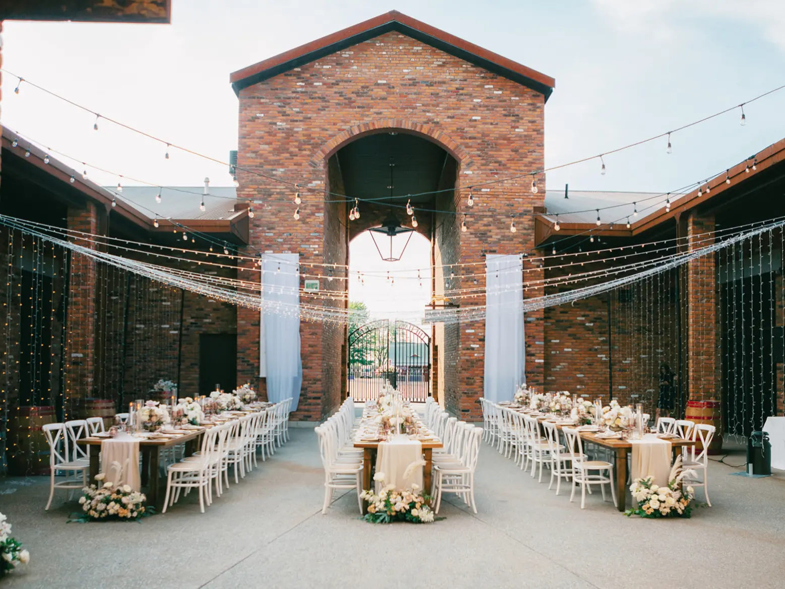 The brick courtyard set with round tables and florals for a wedding