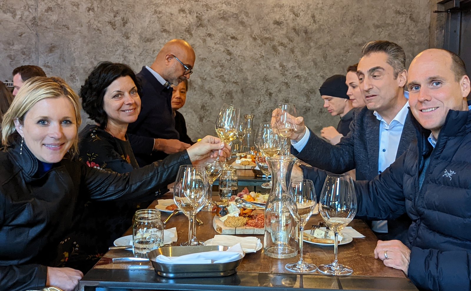 A corporate group along a long table with wine and food