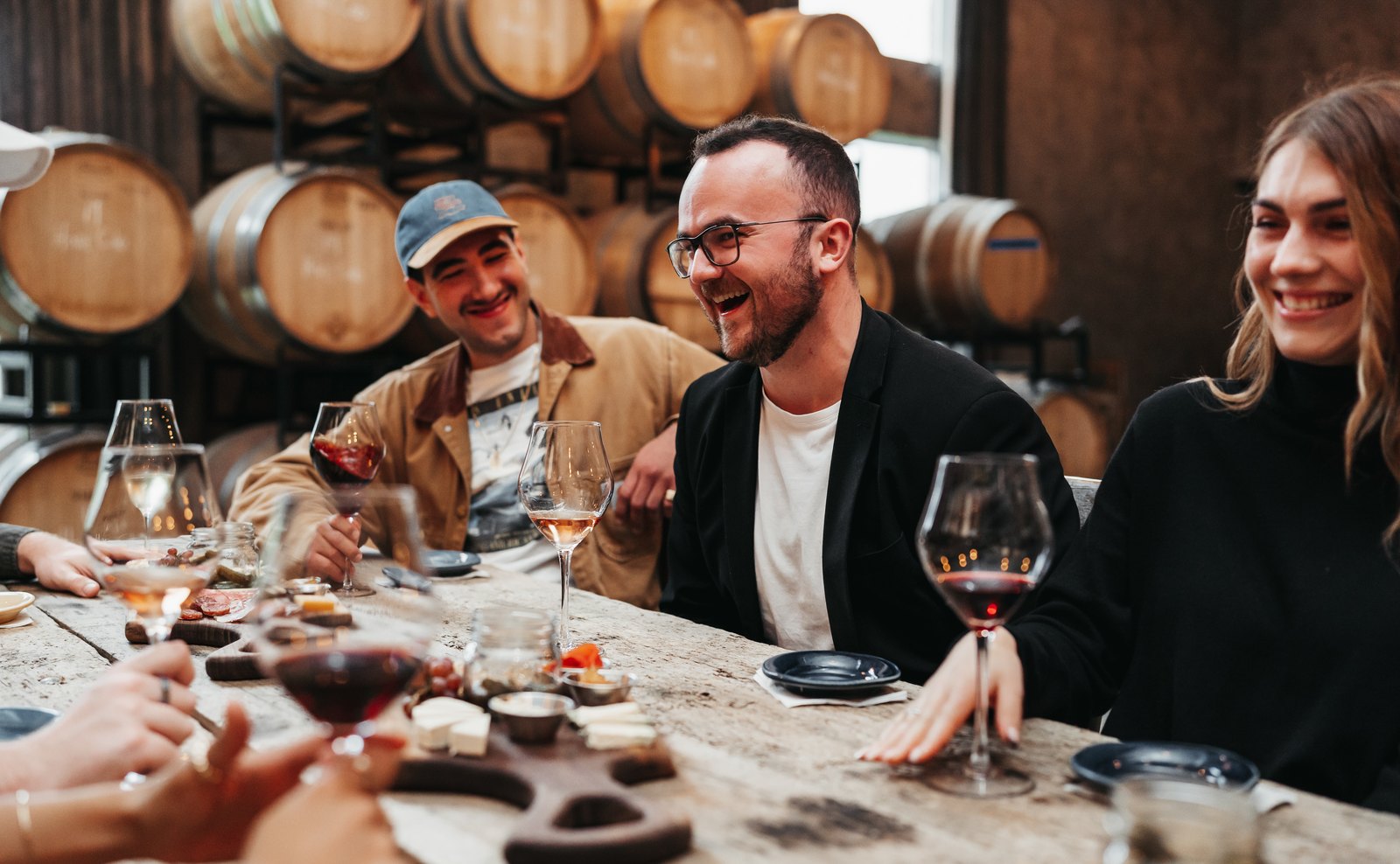 Guests around a long table in the barrel room, mid-tasting