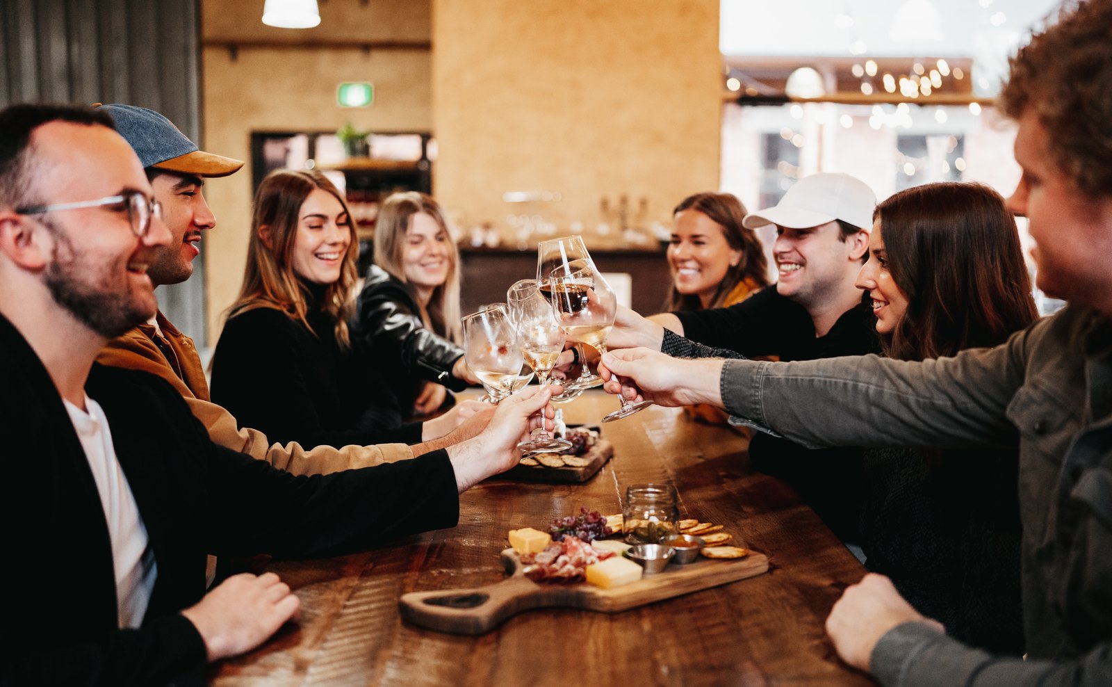 Friends reaching across a table to toast over charcuterie boards