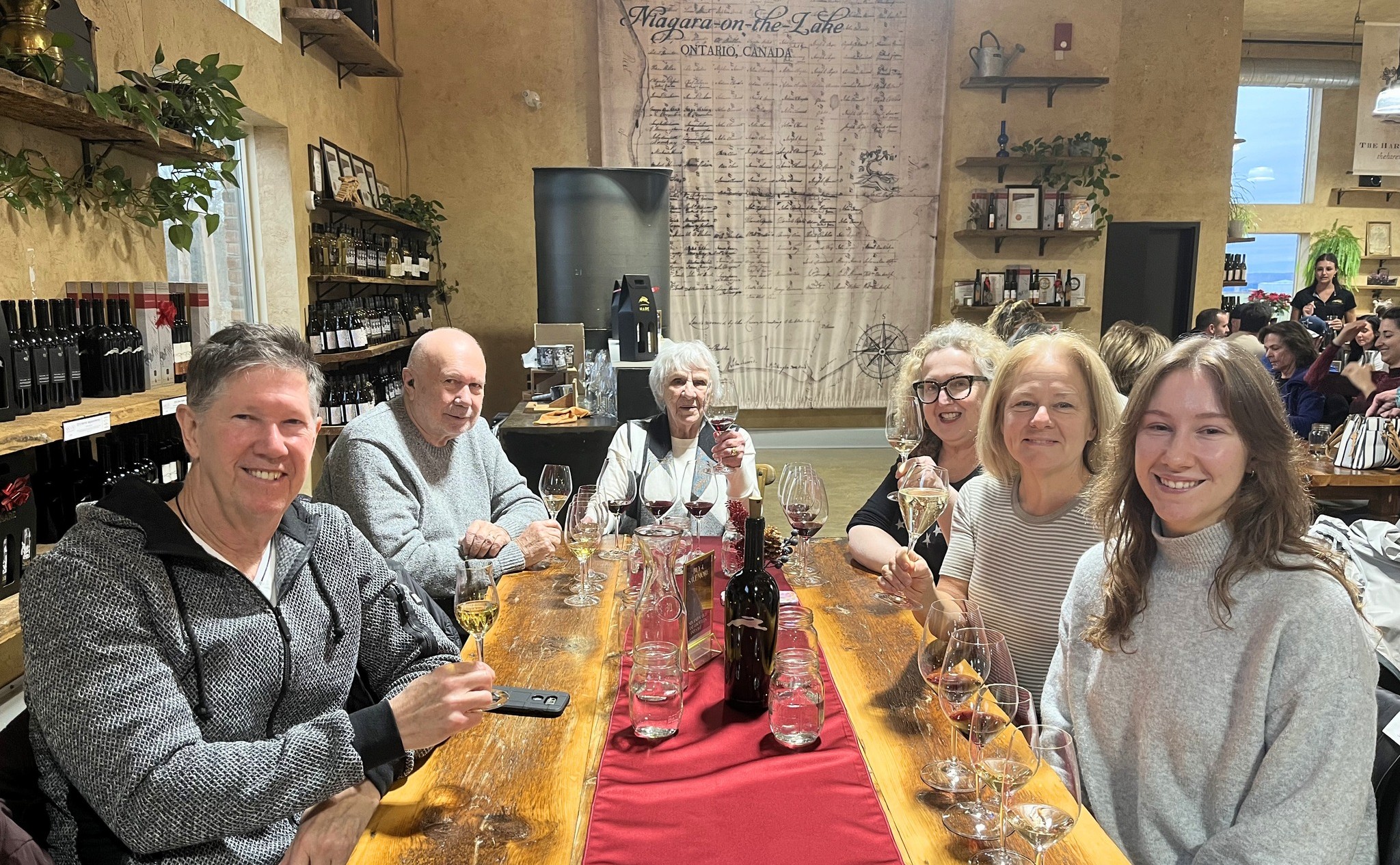 A group along a harvest table in the tasting room, bottles down the centre