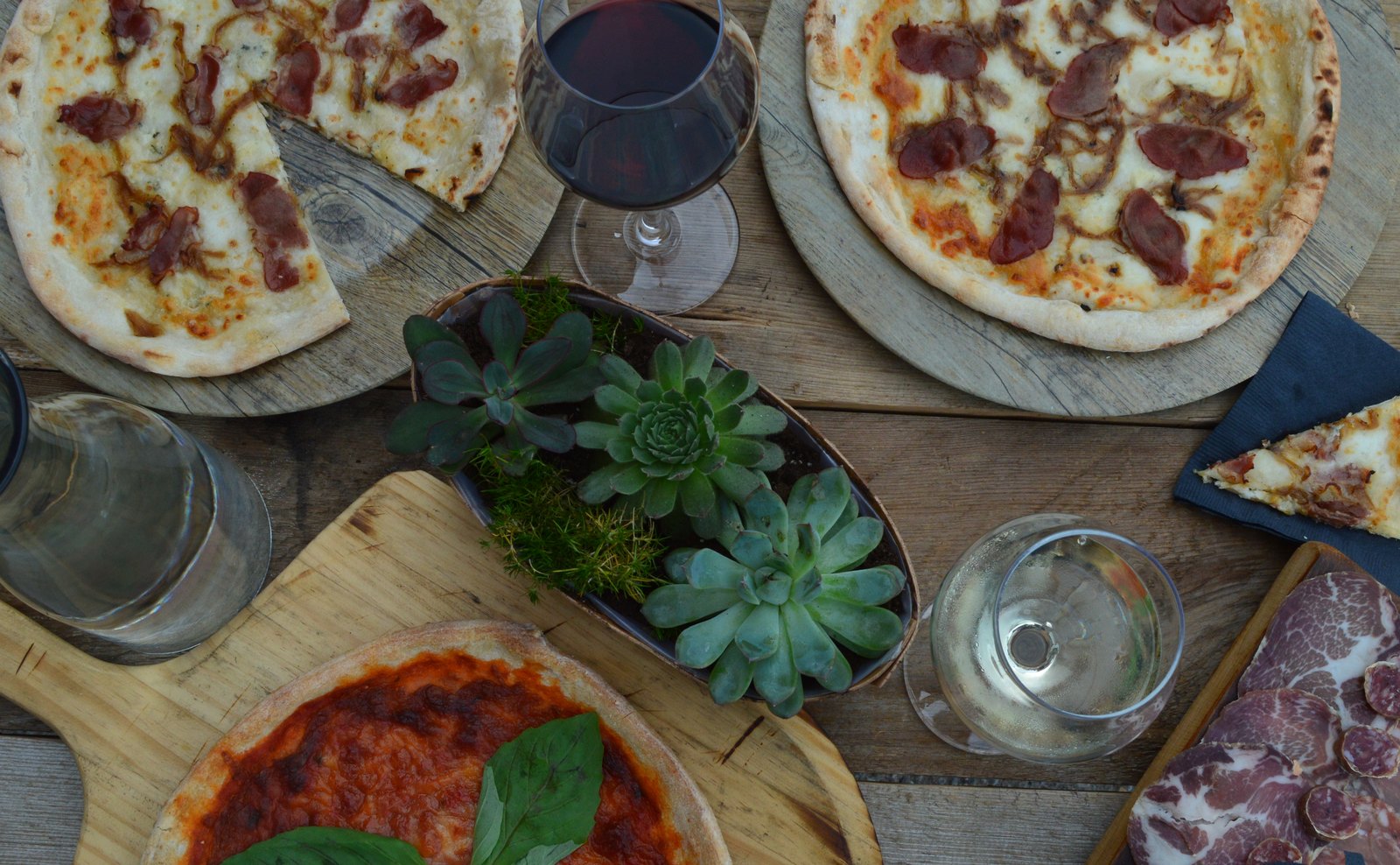 Wood-fired pizza, charcuterie and glasses of wine, seen from above