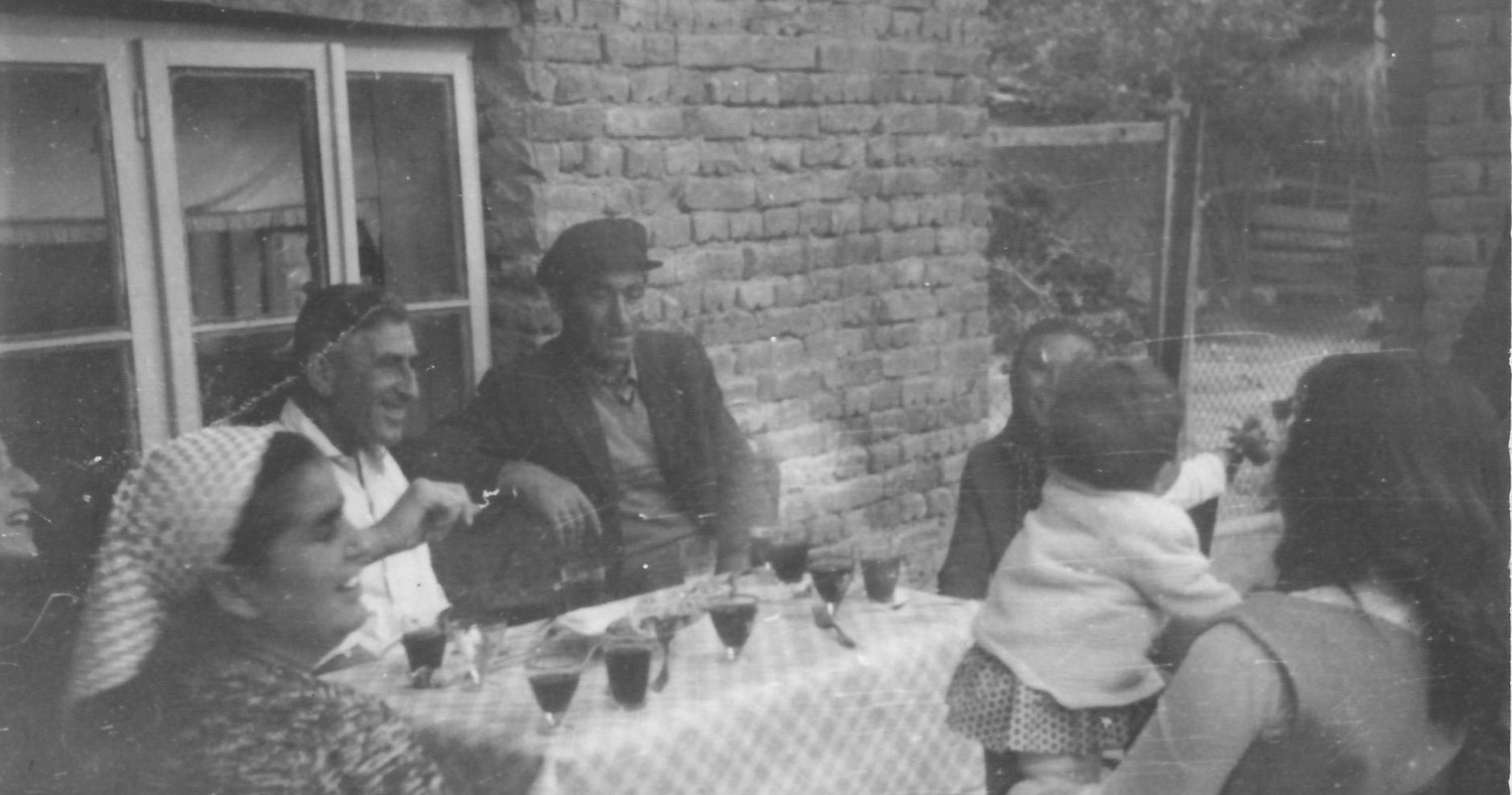 An old family photograph: a table laid outside a brick house