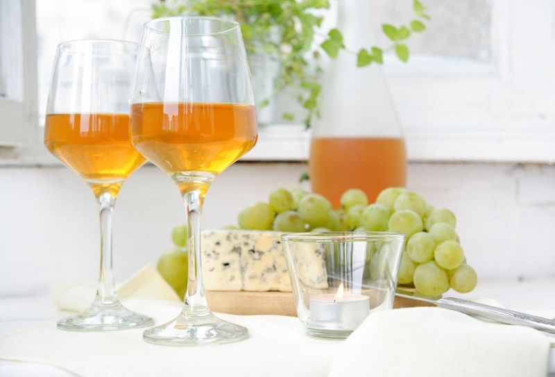 Two white wine glasses paired with blue cheese and white grapes